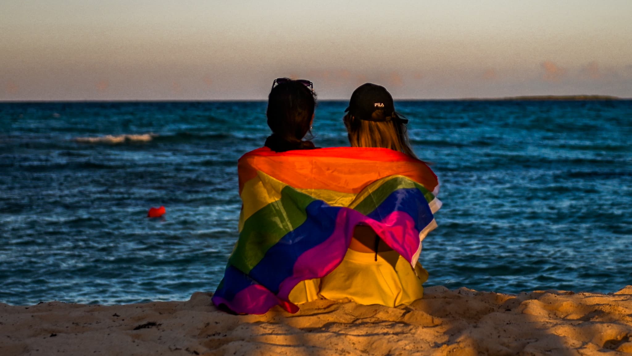 Deux femmes assises le long de la plage avec un drapeau LGBT sur les épaules, dans un hôtel de Guillermo Key (Cuba), le 27 novembre 2021. Deux femmes assises le long de la plage avec un drapeau LGBT sur les épaules, dans un hôtel de Guillermo Key (Cuba), le 27 novembre 2021.