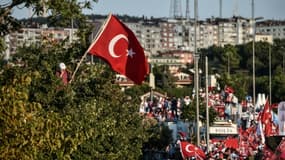Un homme, tenant le drapeau turc, parle au téléphone, lors d'un rassemblement pour la commémoration du premier anniversaire du putsch manqué, le 15 juillet 2017 à Istanbul