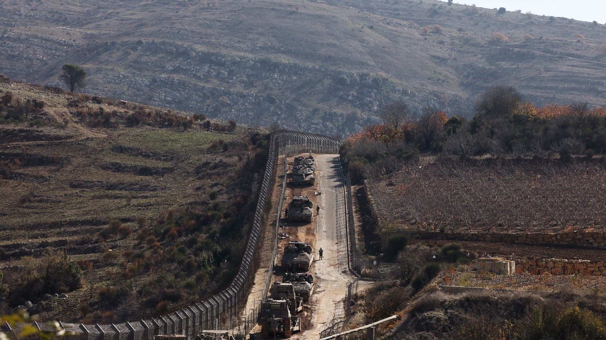 Des véhicules blindés israéliens alignent la zone à l'extérieur du village druze de Majdal Shams sur la clôture de la zone tampon qui sépare le plateau du Golan annexé par Israël du reste de la Syrie, le 9 décembre 2024.