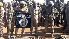 Soldats tchadiens posant avec un drapeau d'Aqmi et des munitions qu'ils ont récupérées à Tessalit, dimanche 3 mars.