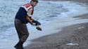 Un officier de police turc devant le corps d'un enfant migrant retrouvé mort sur une plage de Bodrum, au sud de la Turquie, le 2 septembre 2015.