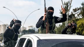 Les forces de sécurité fidèles au gouvernement syrien intérimaire font un geste à l'arrière d'un véhicule circulant sur une route de la ville de Lattaquié, dans l'ouest de la Syrie, le 9 mars 2025.