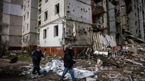 Un couple marche devant un immeuble résidentiel atteint par les bombardements sur la ville ukrainienne de Tcherniguiv le 4 mars 2022