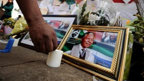 Un homme enflamme une bougie près des portraits de Nelson Mandela devant la clinique de Pretoria, le 11 juillet 2013.
