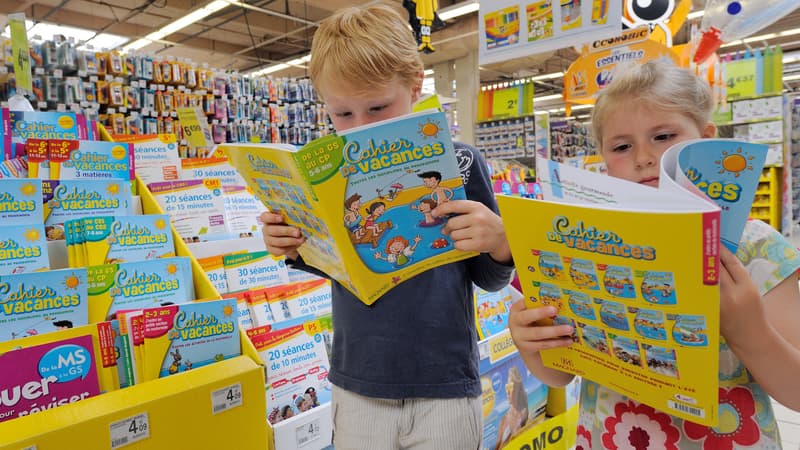 Des enfants feuillettent un cahier de vacances à Englos, en 2013