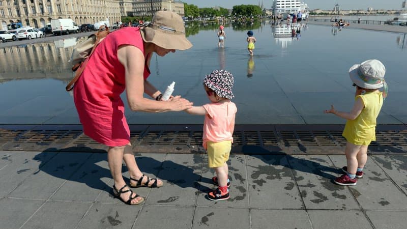 Une femme en train d'appliquer de la crème solaire à une enfant. 