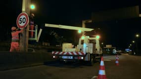 Un ouvrier installe un panneau de limitation à 50 km/h sur le périphérique au niveau de la porte d'Ivry, à Paris, le 30 septembre 2024