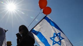Des personnes portant des drapeaux nationaux longent une rue en attendant la procession funéraire des Bibas dans le kibboutz Nir Oz, dans le sud d'Israël, le 26 février 2025. (Photo d'illustration)