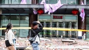 Deux personnes passent devant des débris suite à une explosion dans le grand magasin Shin Kong Mitsukoshi à Taichung, le 13 février 2025.