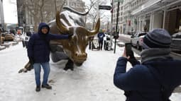 Un touriste pose devant la statue du taureau de Wall Street dans un froid extrême à New York, aux États-Unis, le 27 janvier 2026.