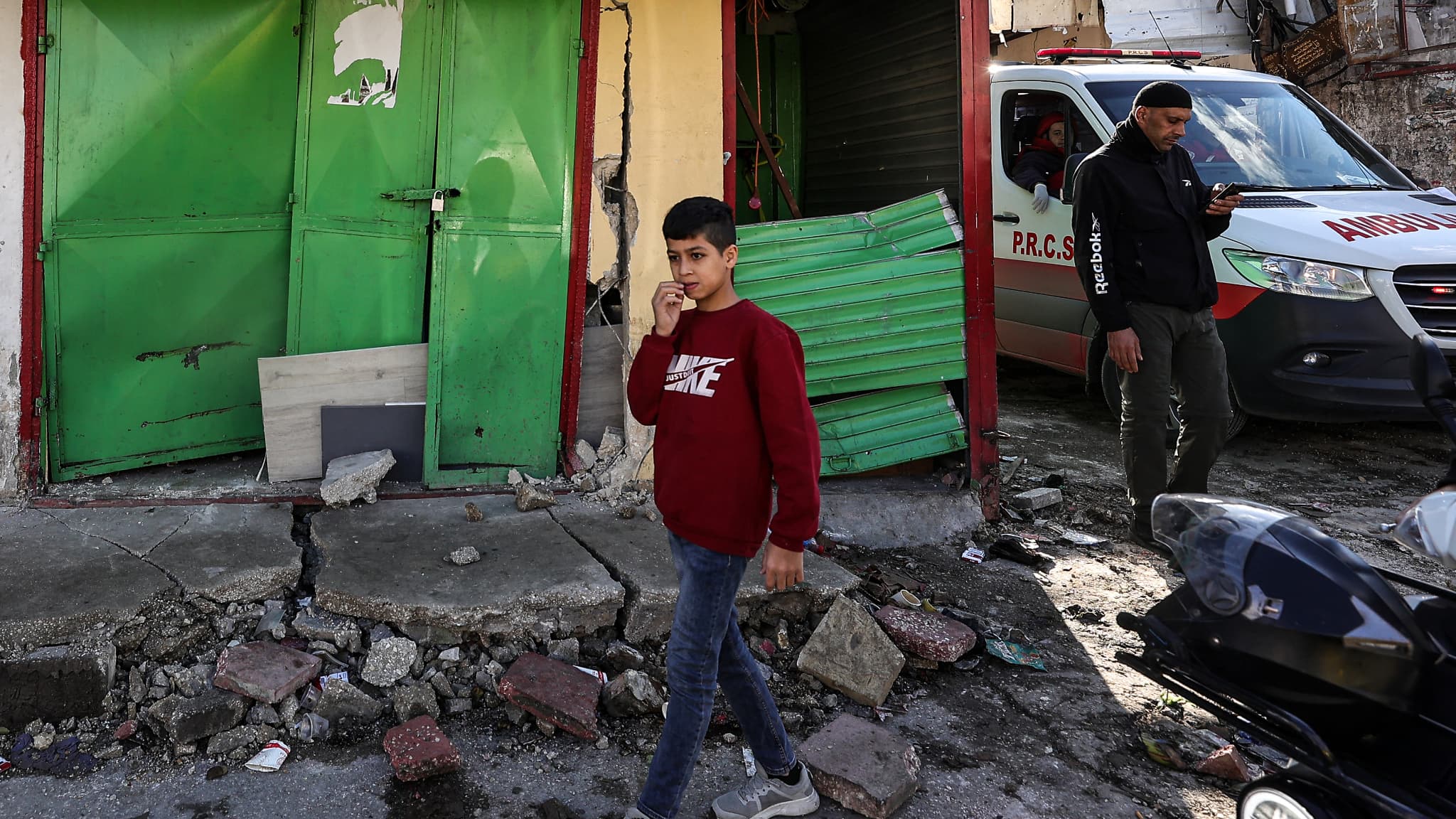 Un jeune Palestinien marche à travers les dégâts causés par un raid de l'armée israélienne dans le camp de réfugiés de Balata, à l'est de la ville de Naplouse, en Cisjordanie, le 21 novembre 2023.