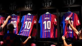 Des clients de la boutique officielle du FC Barcelone examinent des maillots de l'attaquant argentin Lionel Messi, le 7 août 2021 au Camp Nou, deux jours après l'annonce de son départ du club
