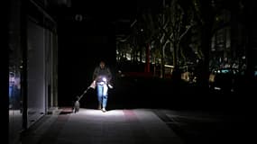 Un passante promène son chien en s'éclairant avec son téléphone, le 28 avril 2025 à Vigo, dans le nord-ouest de l'Espagne, pendant une panne d'électricité géante