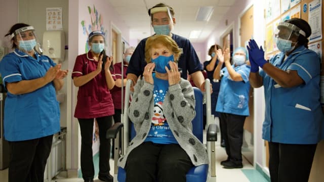 Margaret Keenan (C), applaudie par le personnel soignant après avoir reçu une dose du vaccin Pfizer/BioNTech à Coventry (Royaume-Uni), le 8 décembre 2020