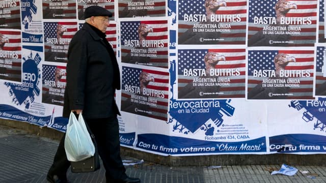Un homme marche devant des affiches qui fustigent les fonds vautours à Buenos Aires.