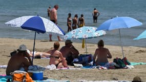 Des personnes sur la plage se protègent du soleil sous des parasols pendant une vague de chaleur à Palavas-les-Flots, dans l'Hérault, le 28 juin 2019.