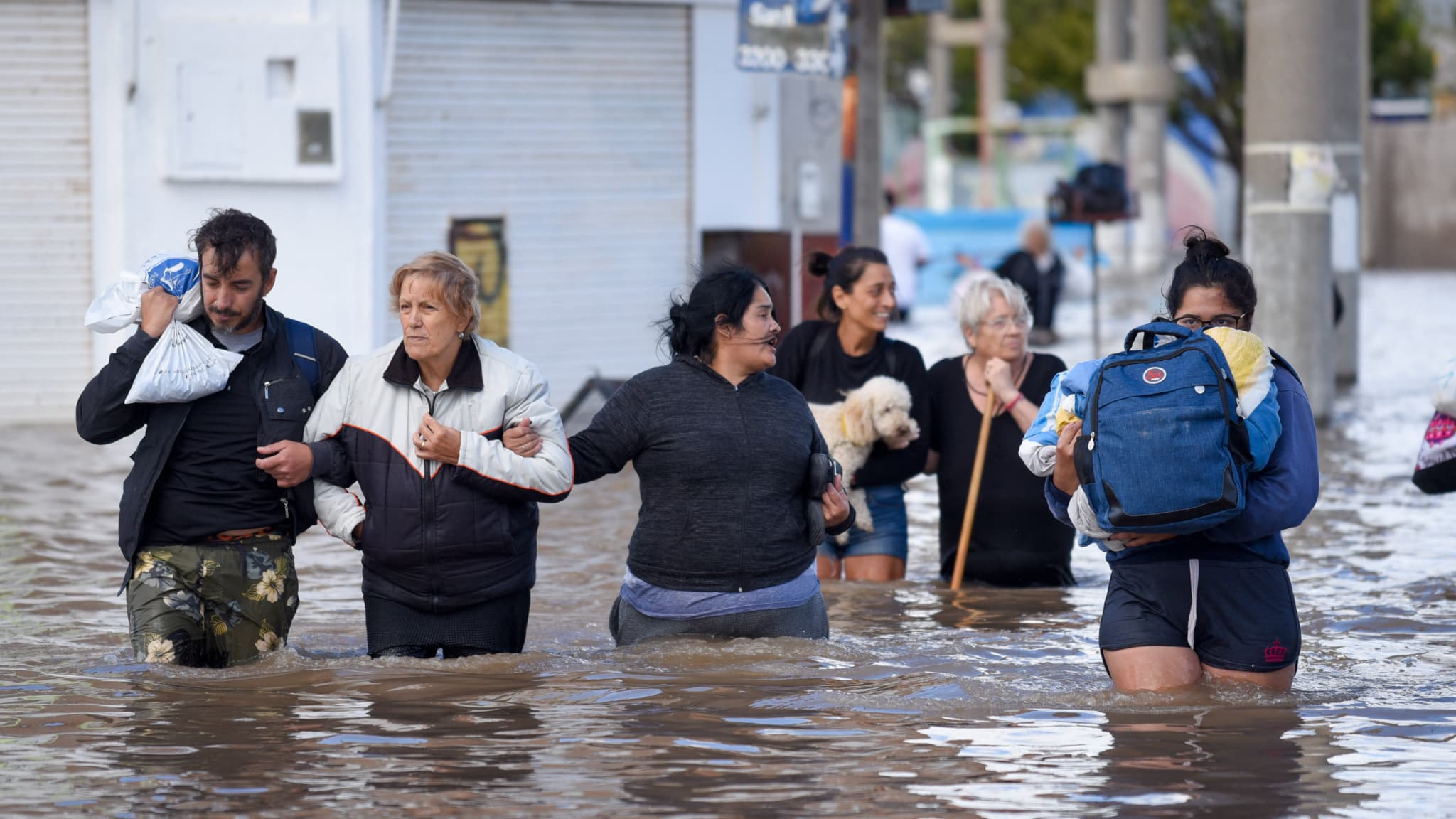 Des personnes marchent dans les eaux inondées au lendemain d'une forte tempête à Bahia Blanca, à 600 km au sud de Buenos Aires, le 8 mars 2025.