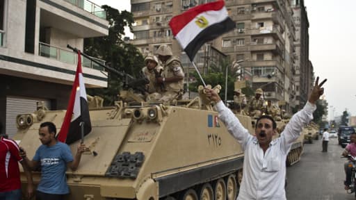 Des Egyptiens saluent mercredi l’action de l’armée dans une rue du Caire.