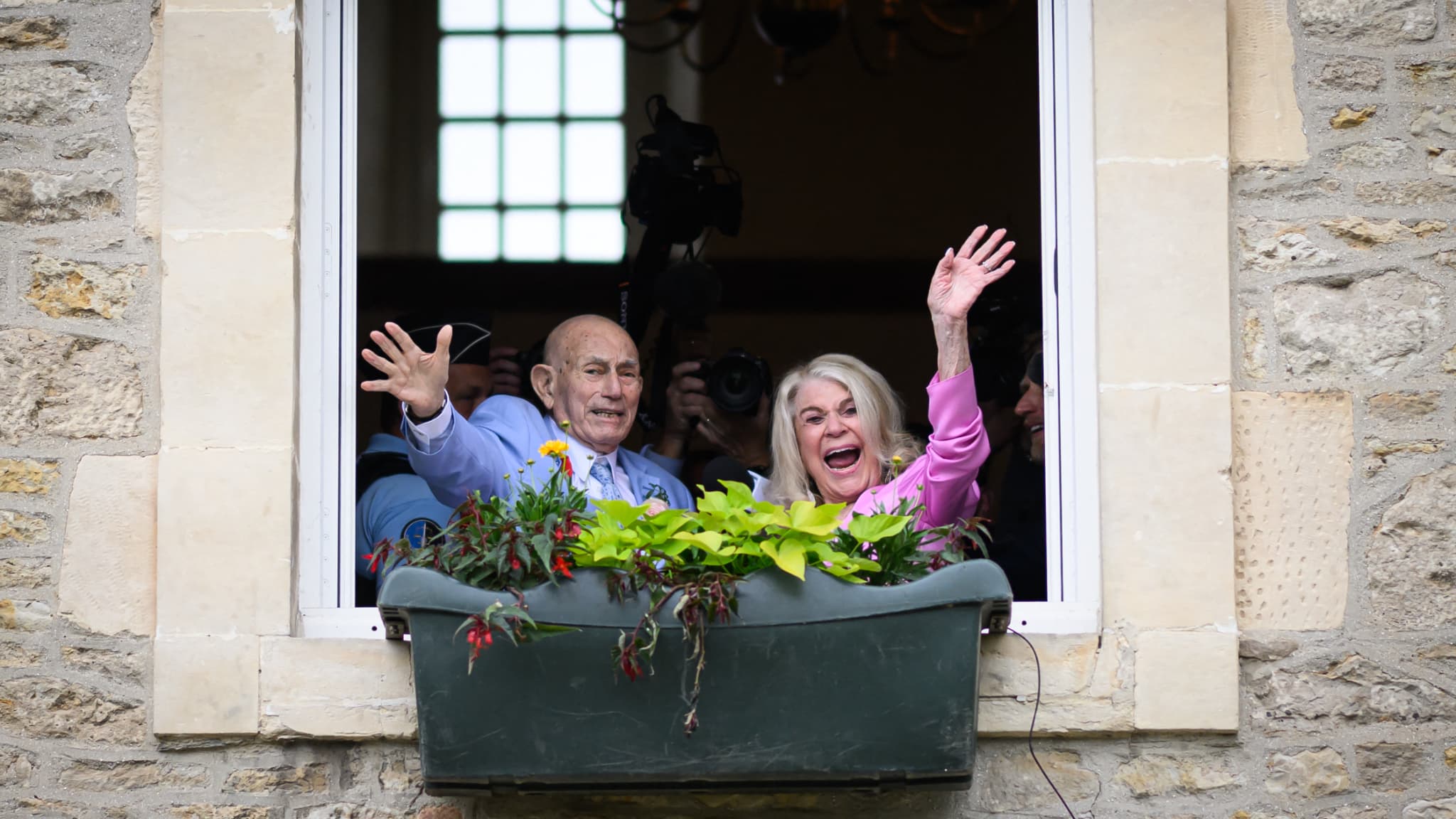 Jeanne Swerlin et Harold Terens saluent la foule depuis une fenêtre alors qu'ils célèbrent leur mariage à la mairie de Carentan-les-Marais.