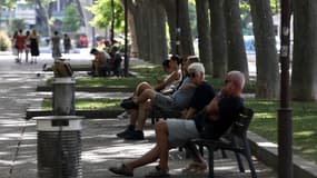 Des personnes assises sur des bancs à l'ombre, à Perpignan ce vendredi, alors que la France est confrontée à une vague de chaleur précoce.