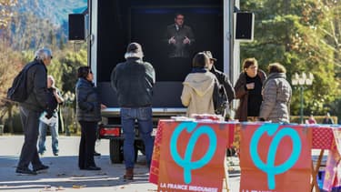 Des passants écoutent l'hologramme de Jean-Luc Mélenchon (LFI) dans un holovan, le 6 février 2019 à Sospel, dans le sud de la France.