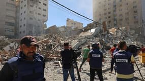 Des journalistes filment les décombres du bâtiment qui abritait les bureaux locaux de la chaîne qatarie Al-Jazeera et de l'agence internationale américaine Associated Press (AP) le 15 mai 2021 à Gaza