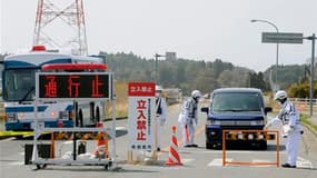 Des policiers postés à la limite du périmètre d'évacuation de 20 km autour de la centrale nucléaire de Fukushima-Daiichi renseignent des habitants quittant ce secteur (les panneaux indiquent "route bloquée" et "entrée non autorisée"). Cette zone autour de