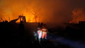 Pompiers à l'oeuvre sur le site d'une explosion dans la banlieue est de Rangoun, en Birmanie. Au moins 17 personnes sont mortes et 80 ont été blessées. /Photo prise le 29 décembre 2011/REUTERS/Soe Zeya Tun