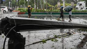 Des personnes passent devant un poteau électrique tombé à cause des vents violents de la tempête tropicale Yagi à Manille, aux Philippines, le 2 septembre 2024. 