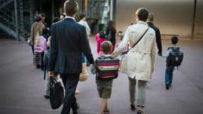 Des parents et leur enfant dans une cour d'école (photo d'illustration)