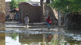 Sur cette photo prise le 28 août 2022, des villageois pataugent dans les eaux de crue à la périphérie de Sukkur, dans la province du Sindh, au Pakistan.