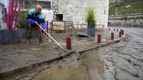 Un homme nettoie la boue sur un trottoir à Anduze, le 19 septembre 2020