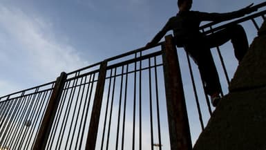 Un migrant escalade une clôture de l'enclave espagnole de Melilla à la frontière du Maroc, le 16 mai 2017