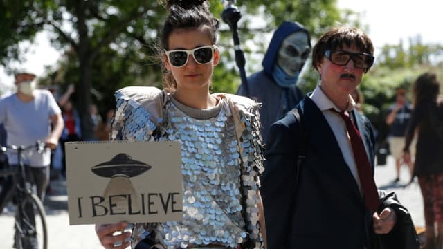 Une femme tient une pancarte "je crois" aux ovnis, lors d'une manifestation contre les tenants des théories du complot à Berlin le 30 mai 2020