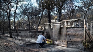 Un expert marque le portail d'une maison brûlée dans le village de Neos Voutzas, près d'Athènes le 26 juillet 2018.
