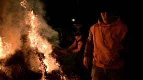 Des agriculteurs français et des membres du syndicat agricole Coordination Rurale (CR) se rassemblent autour d'un feu pendant le blocage du port de Bordeaux, à Bassens, le 20 novembre 2024