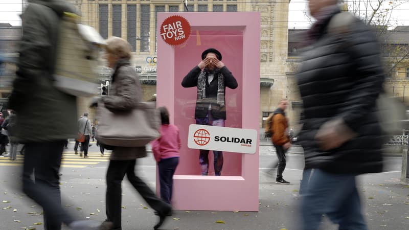 Un homme prend la pose dans un immense emballage contre les conditions de travail en Chine, à Lausanne en Suisse.