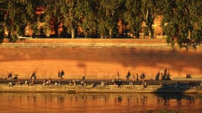 Des personnes sont assises sur les rives de la Garonne au coucher du soleil à Toulouse, dans le sud-ouest de la France, le 30 septembre 2023 (Photo d'illustration).