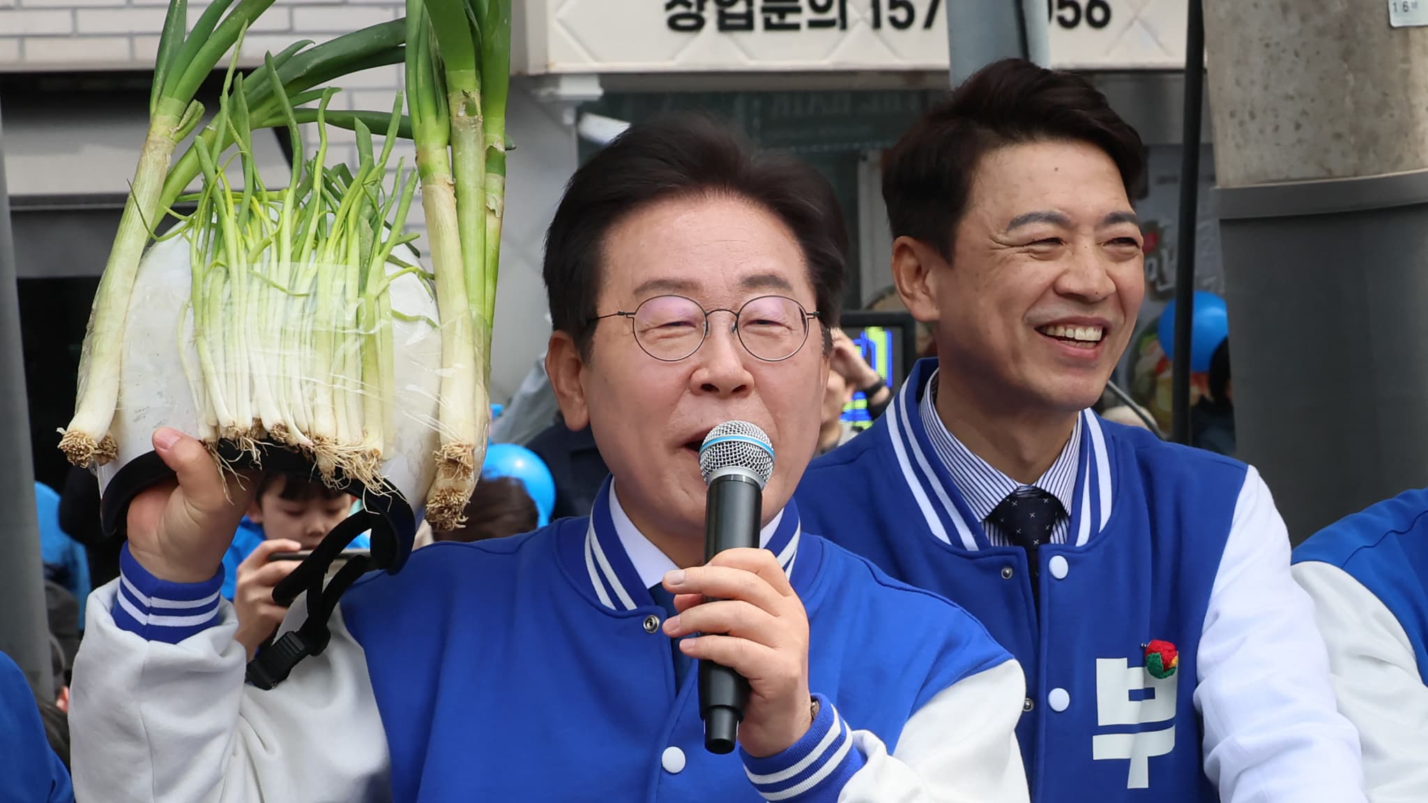 Le leader du principal parti d'opposition sud-coréen Lee Jae-myung brandit des oignons verts le 5 avril 2024 lors d'un événement de campagne pour les législatives. 