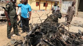 Policiers autour de la voiture piégée utilisée dans l'attentat qui a visé dimanche l'église catholique Sainte-Theresa à Madala, près de la capitale nigériane Abuja. L'attaque a été revendiquée par la secte islamiste Boko Haram. /Photo prise le 25 décembre