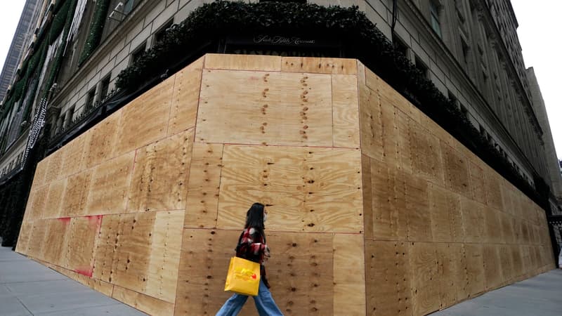 Une passante marche à côté d'un magasin barricadé à New York.