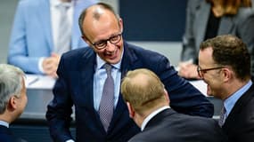 Le chancelier allemand Friedrich Merz (à gauche) et le chef du groupe parlementaire de l'Union chrétienne-démocrate (CDU) Jens Spahn (à droite) partagent un moment de détente avec les députés avant une séance du Bundestag, la chambre basse du parlement allemand, à Berlin le 5 décembre 2025.