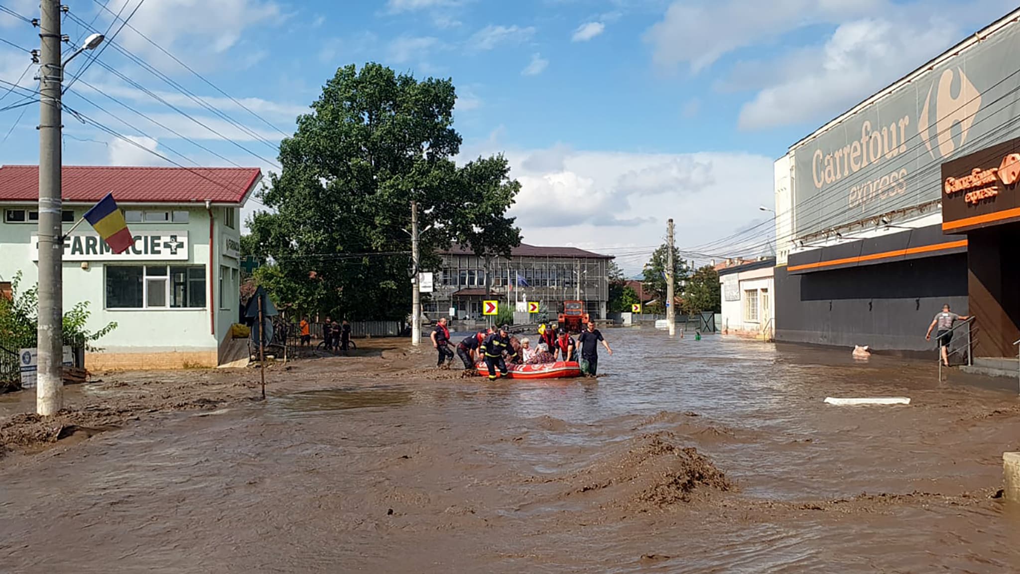 Cette photo prise le 14 septembre 2024 montre des secouristes aidant des personnes assises dans un bateau en caoutchouc à sortir des inondations à Pechea, dans le comté de Galati, en Roumanie.