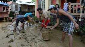 Les habitants enlèvent la boue le 20 octobre 2015 dans les rues de Cabanatuan City, au nord de Manille, apportée par les fortes pluies occasionnées par le typhon Koppu qui a fait au moins 22 morts