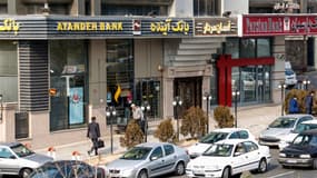 Des Iraniens passent devant un établissement de la banque Ayandeh, à Téhéran, le 14 janvier 2017. 