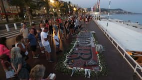 Des gens se rassemblent autour d'un mémorial de fortune le 14 juillet 2017 sur la "Promenade des Anglais" à Nice, dans le sud de la France, après une cérémonie commémorative marquant le premier anniversaire de l'attaque d'un camion jihadiste qui a tué 86 personnes le 14 juillet 2016