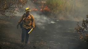 Un pompier de la ville de Los Angeles marcahnt à travers une forêt carbonisée à Redding en Californie, le 29 juillet 2018