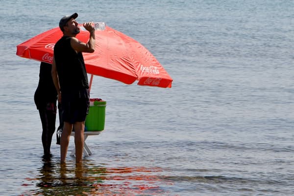 Un Tunisien s'hydrate sur une plage de Tunis, le 24 juillet 2023 