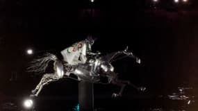 Floriane Issert, sous-officier de gendarmerie de la Gendarmerie nationale, monte sur un cheval mécanique en métal, remonte la Seine, enveloppée dans le drapeau olympique lors de la cérémonie d'ouverture des Jeux Olympiques de Paris 2024 à Paris le 26 juillet 2024. Emmanuel DUNAND / AFP