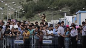 Des migrants dans un camp de réfugiés en Turquie, essayant d'apercevoir la chancelière allemande Angela Merkel, en visite officielle, le 23 avril 2016.